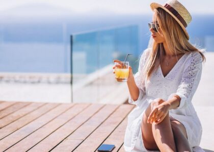 Giovane donna che beve un succo in piscina durante la sua esperienza di turismo di lusso in Italia.