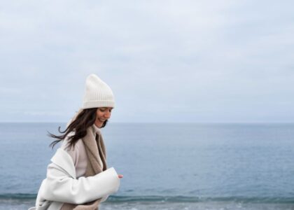 Donna sorridente in spiaggia d'inverno, a simboleggiar il turismo in bassa stagione.